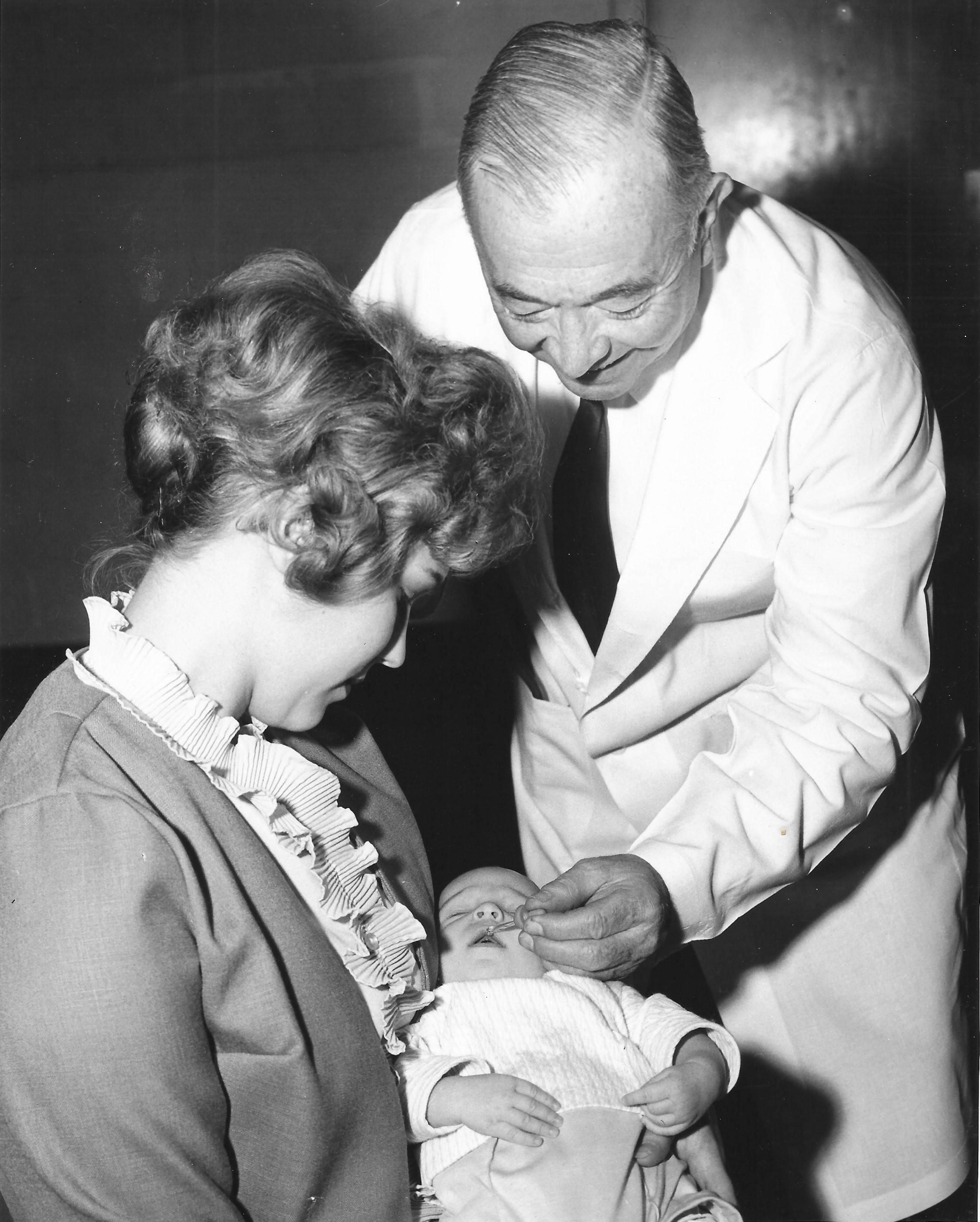 Dr. Robert Rogoff of Charity Hospital vaccinates infant Lecia Lynn Carter.
